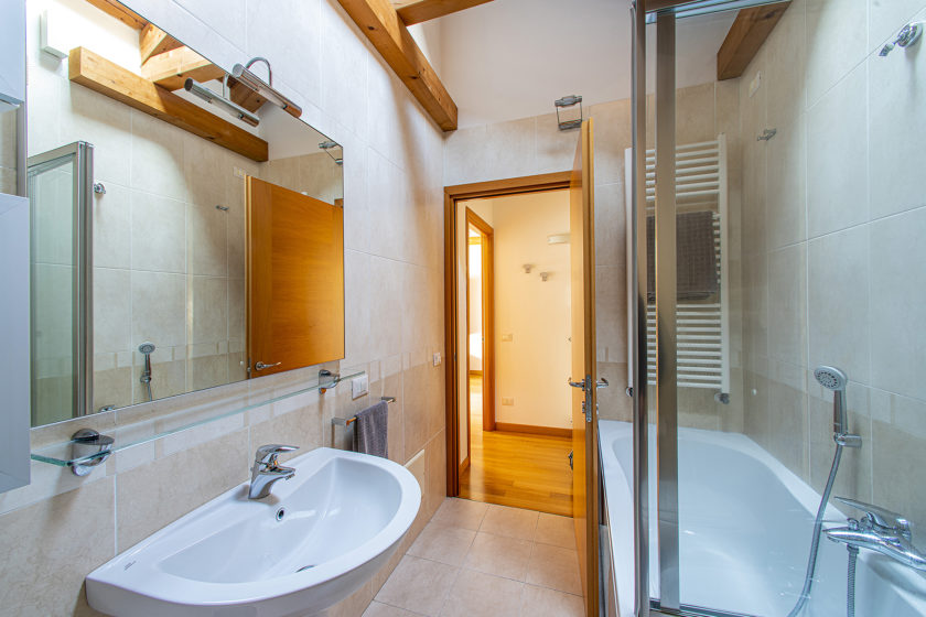 Bagno con vasca, doccia e specchiera, con ampia porta di accesso